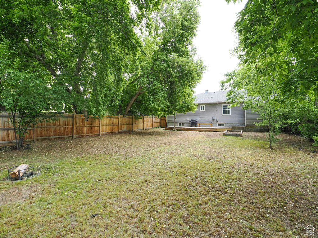 View of yard with a deck, an outdoor fire pit, and a fenced backyard