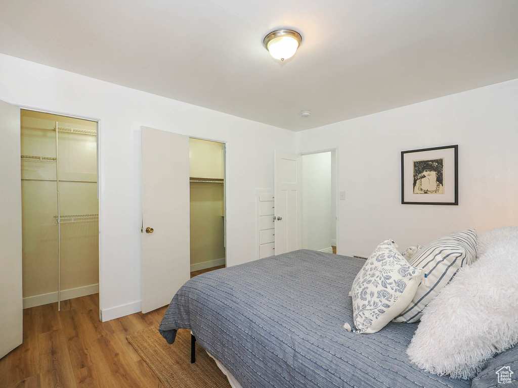 Bedroom featuring two closets, a spacious closet, baseboards, and wood finished floors