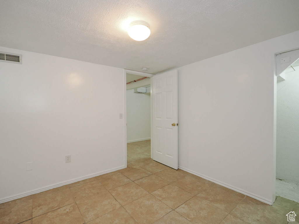 Empty room with visible vents, a textured ceiling, baseboards, and light tile patterned floors