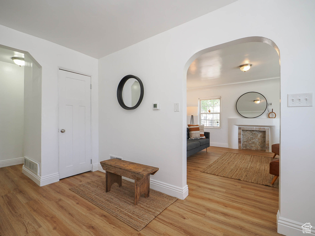 Corridor featuring light wood-style floors, visible vents, arched walkways, and baseboards