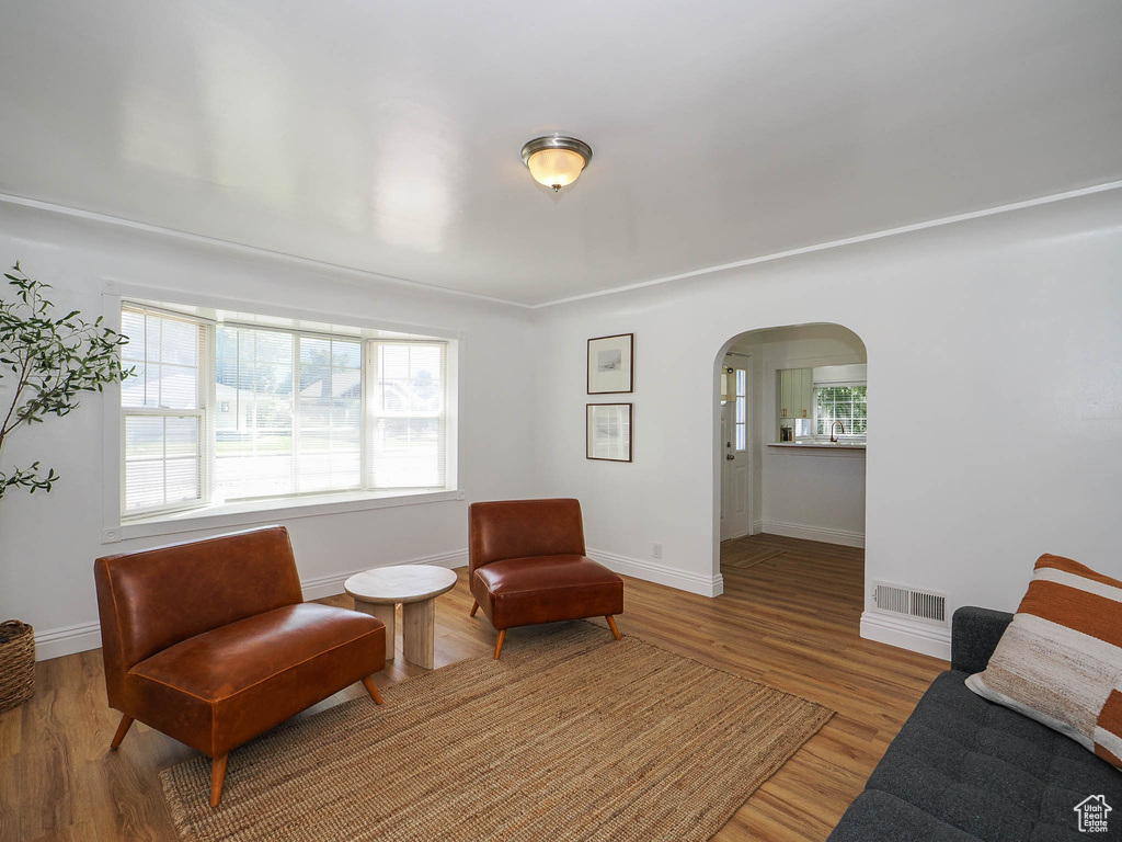 Sitting room featuring baseboards, visible vents, arched walkways, and wood finished floors