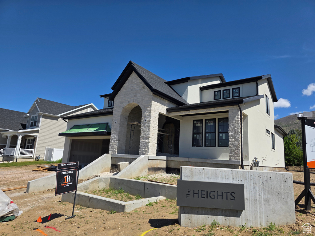 French country home with an attached garage, stone siding, and stucco siding