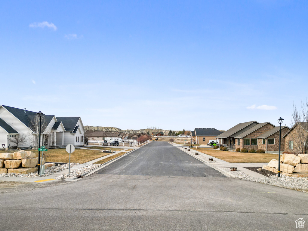 View of road featuring street lights, sidewalks, curbs, a residential view, and traffic signs