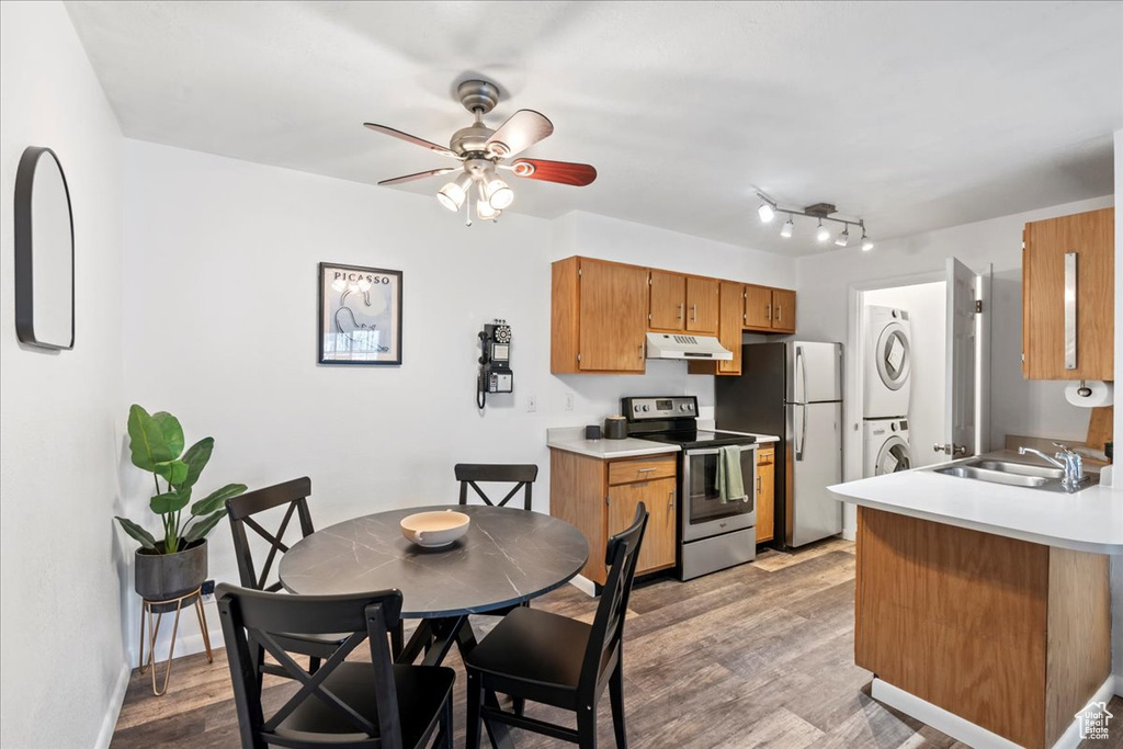 Kitchen featuring stainless steel appliances, stacked washer / dryer, light countertops, and under cabinet range hood