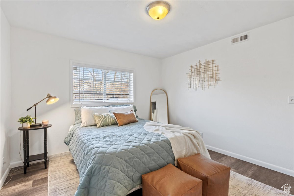 Bedroom with visible vents, baseboards, and wood finished floors