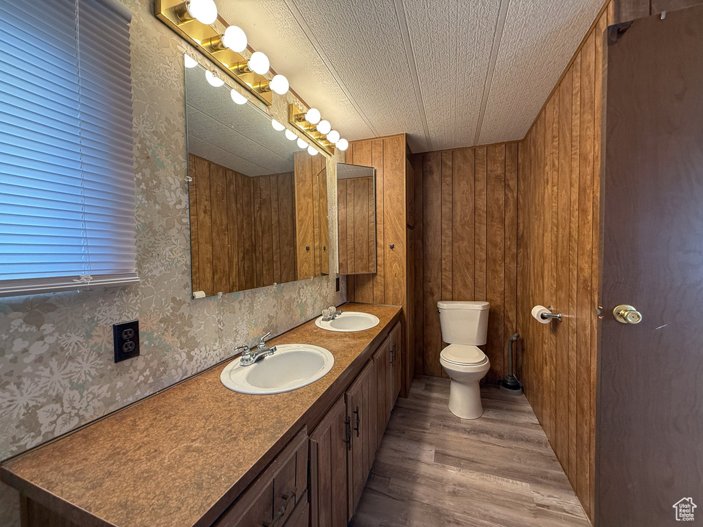 Bathroom featuring double vanity, a sink, toilet, and wood finished floors