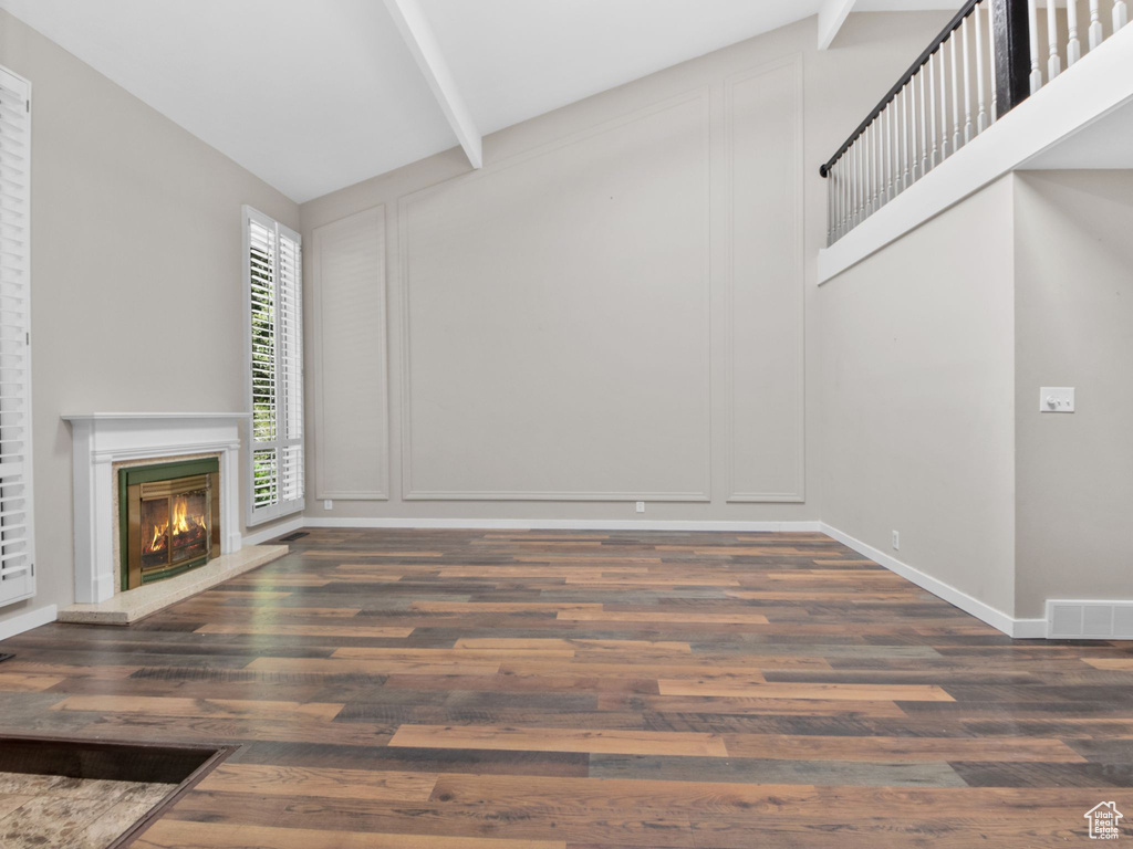 Unfurnished living room featuring wood finished floors, a decorative wall, and a glass covered fireplace