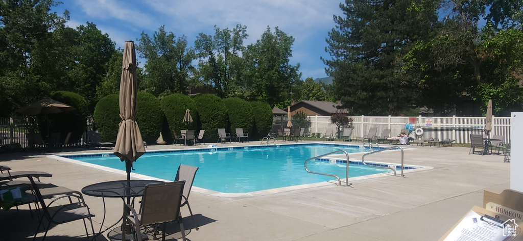 Community pool featuring a patio and view of scattered trees