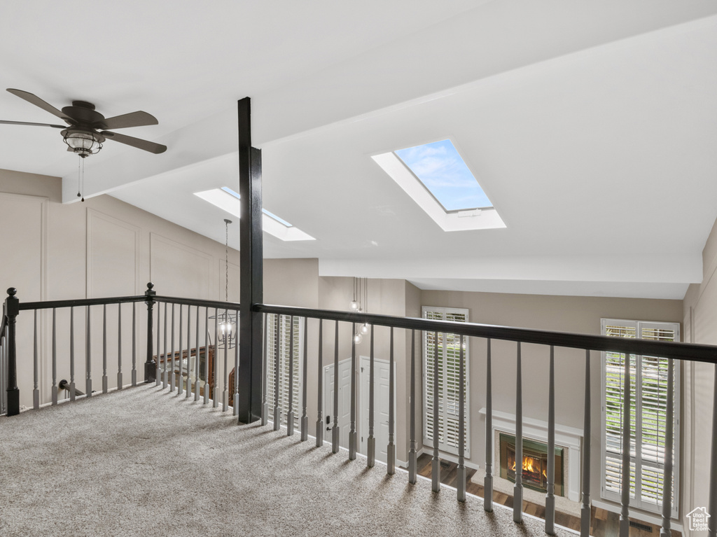 Hall with a skylight, vaulted ceiling, and carpet floors