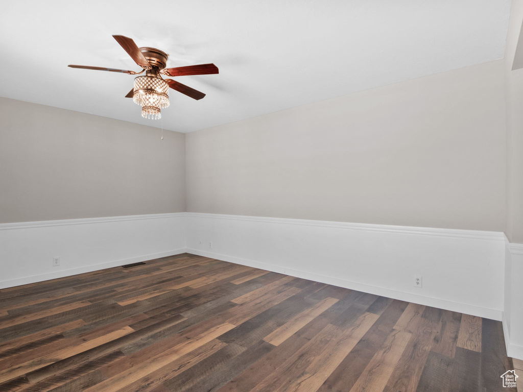 Empty room with ceiling fan and dark wood-type flooring