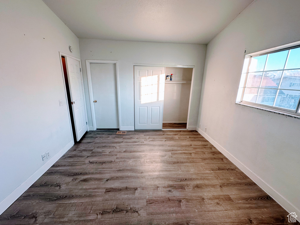 Unfurnished bedroom featuring multiple windows, light wood-style flooring, and baseboards