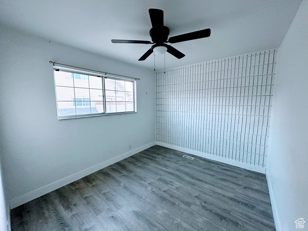 Unfurnished room featuring wood finished floors, visible vents, and baseboards