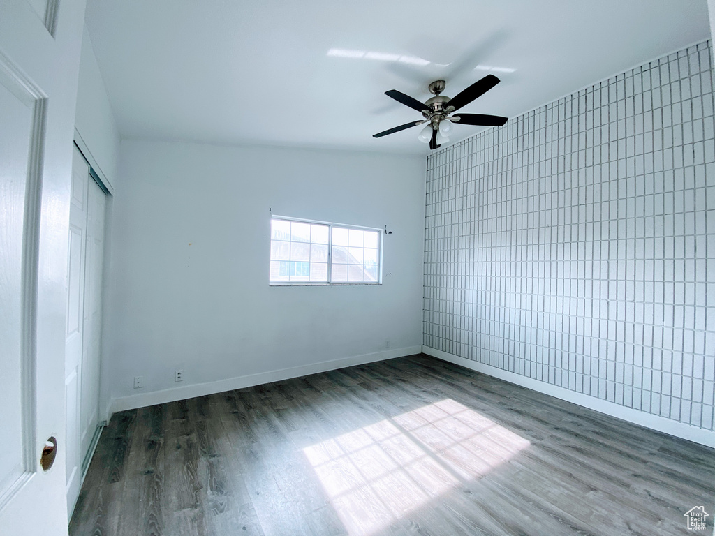 Unfurnished room with ceiling fan, dark wood-style flooring, and baseboards
