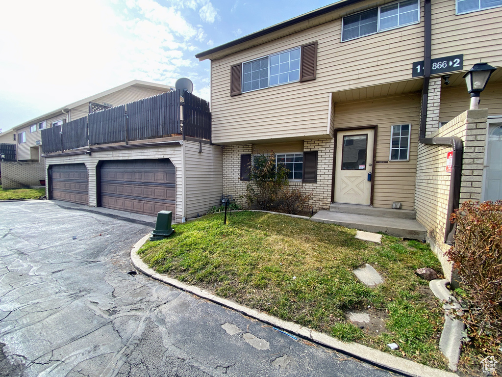 View of property featuring driveway, brick siding, and an attached garage