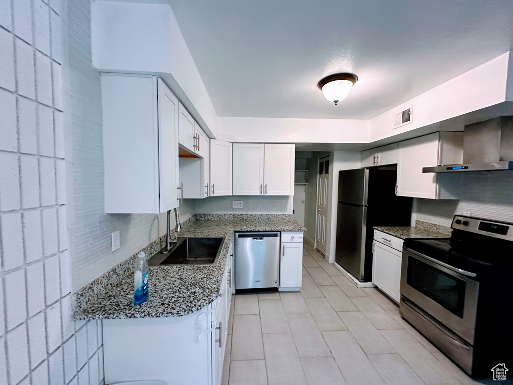 Kitchen with stainless steel appliances, white cabinetry, visible vents, and light stone counters