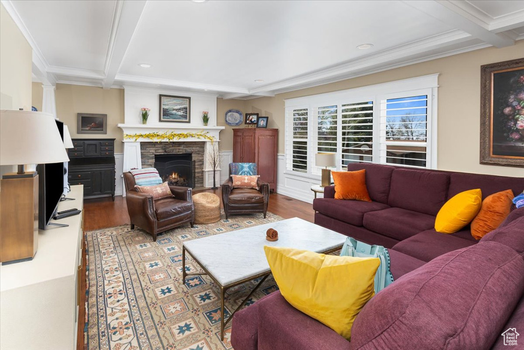Living area with a fireplace, beamed ceiling, ornamental molding, and wood finished floors
