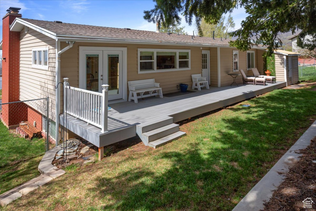 Back of property featuring a chimney, french doors, a wooden deck, and a yard