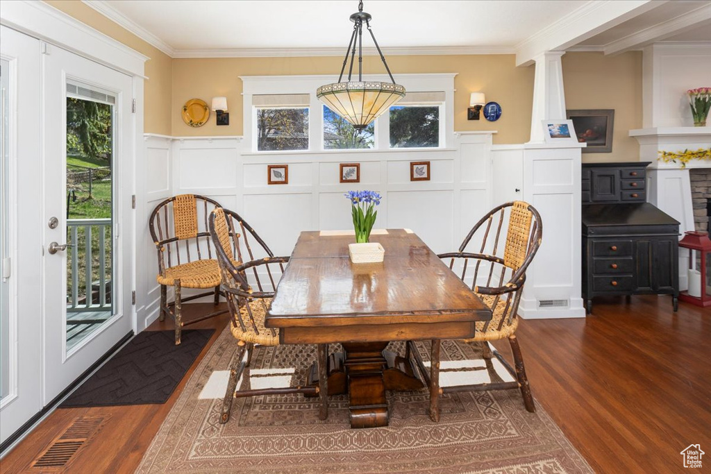 Dining area featuring ornamental molding, dark wood-style floors, a wainscoted wall, visible vents, and a decorative wall