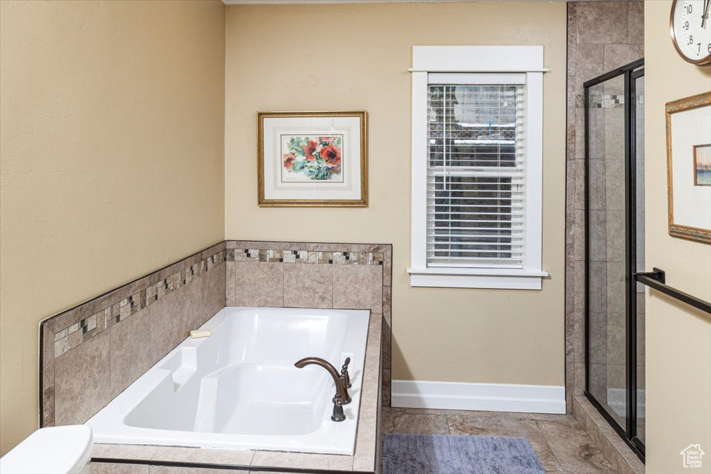 Full bathroom with a shower stall, baseboards, and a bath