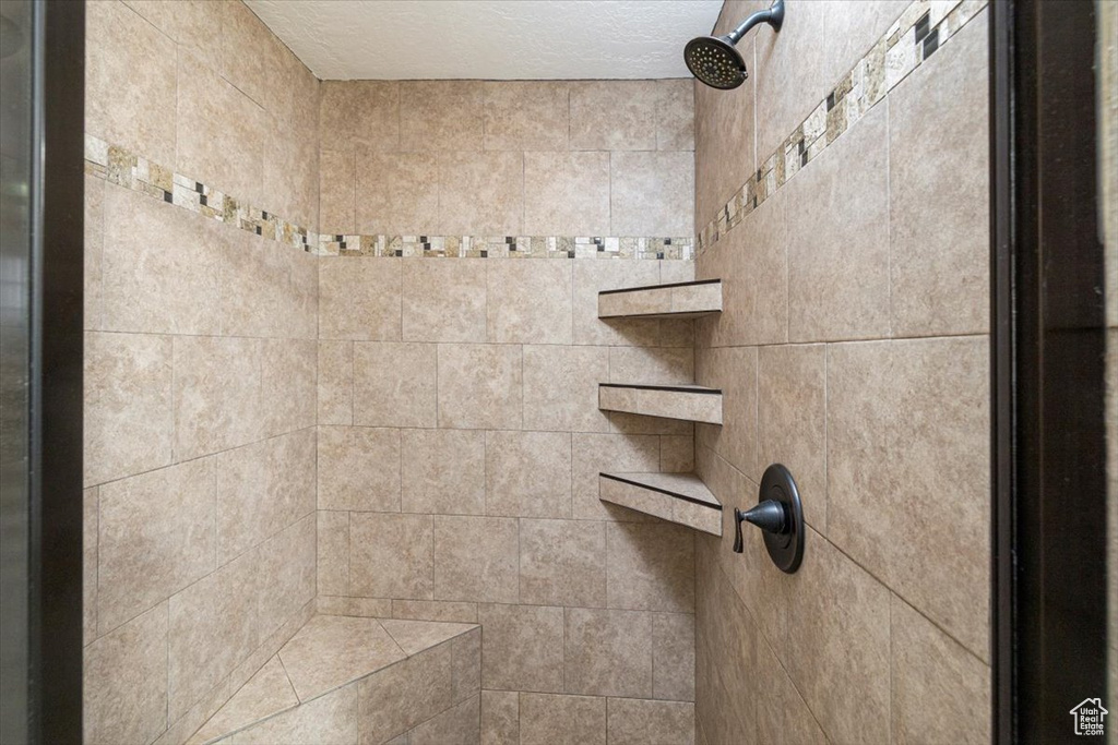 Interior details featuring a textured ceiling and tiled shower