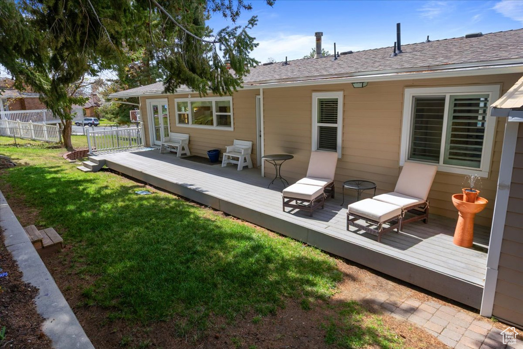Rear view of property featuring fence, a wooden deck, and a lawn