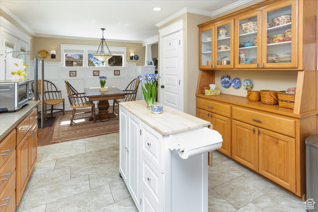 Kitchen with glass insert cabinets, ornamental molding, pendant lighting, a kitchen island, and a toaster