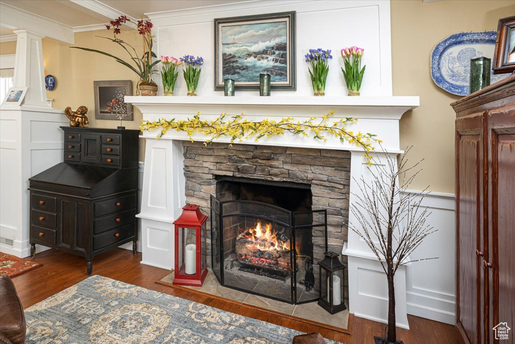 Room details featuring a decorative wall, a fireplace, wood finished floors, and crown molding
