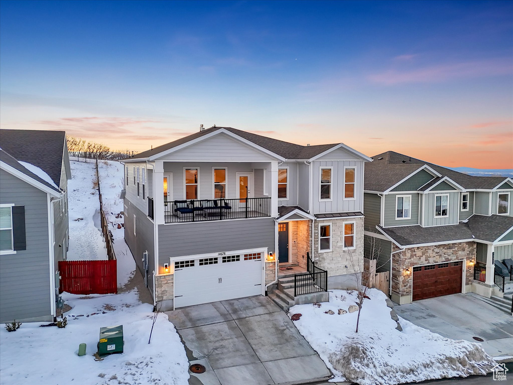 View of front of home with an attached garage, stone siding, driveway, a residential view, and board and batten siding