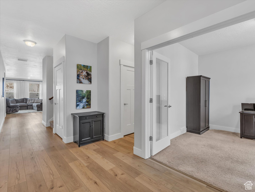 Hallway featuring light wood-style floors, visible vents, and baseboards