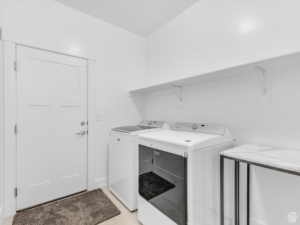 Laundry room featuring laundry area, washer and clothes dryer, and light tile patterned floors