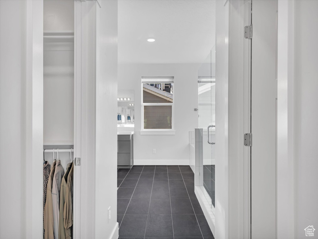 Interior space featuring tile patterned flooring, vanity, baseboards, a spacious closet, and a shower stall