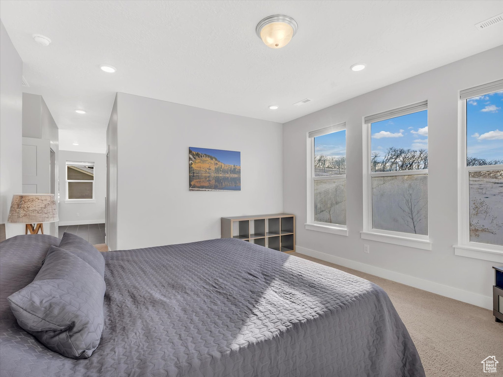 Carpeted bedroom with visible vents, baseboards, and recessed lighting