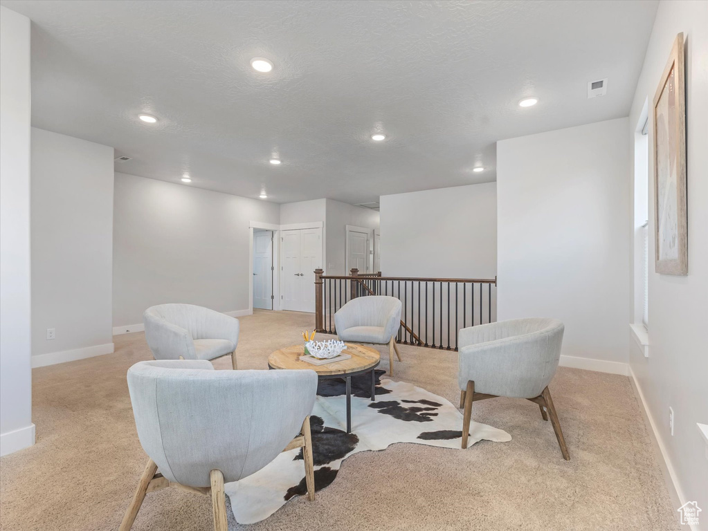 Sitting room featuring light carpet, recessed lighting, and an upstairs landing