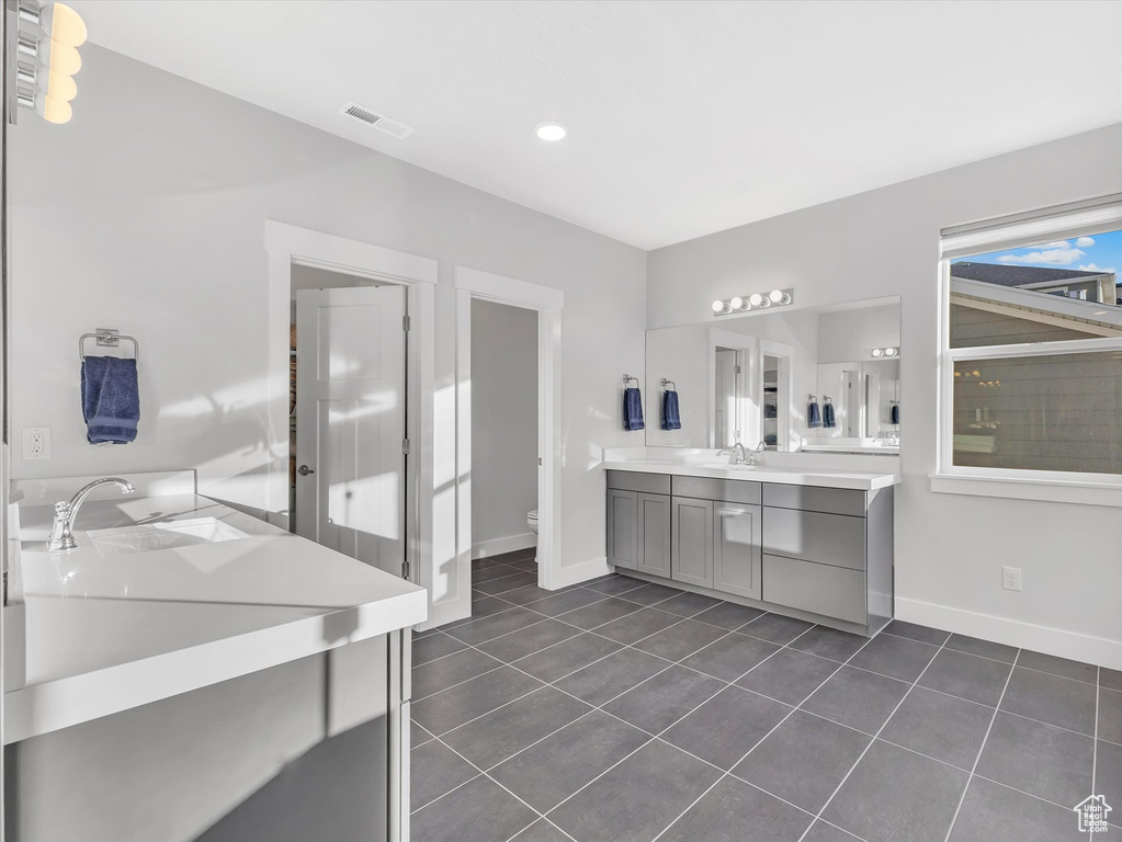 Bathroom featuring tile patterned flooring, toilet, vanity, visible vents, and baseboards