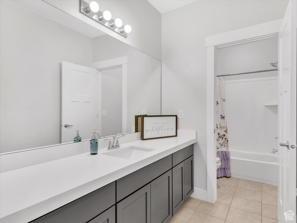 Full bathroom featuring baseboards, shower / bathtub combination with curtain, vanity, and tile patterned floors