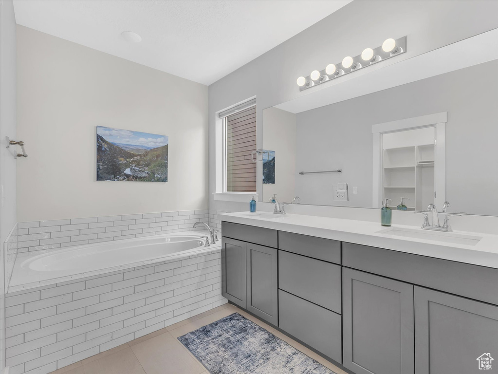 Full bath with a garden tub, double vanity, a sink, and tile patterned floors