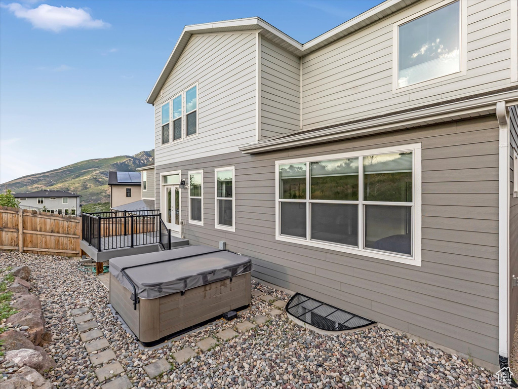 Back of property with a hot tub and a deck with mountain view