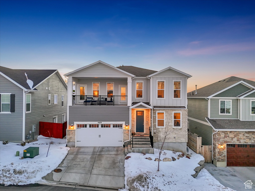 View of front of property with an attached garage, stone siding, board and batten siding, and concrete driveway