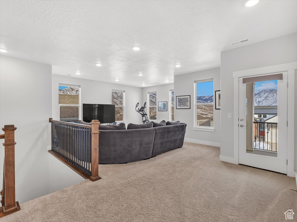 Living room with a textured ceiling, recessed lighting, visible vents, and light colored carpet