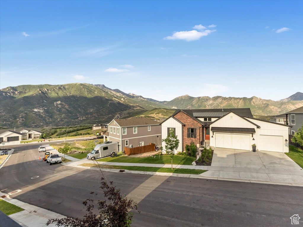 View of front of property with a mountain view, concrete driveway, an attached garage, and brick siding