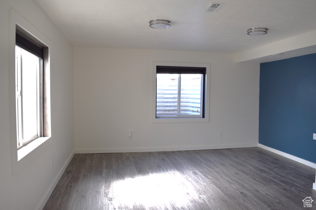 Spare room featuring dark wood-style floors, baseboards, and visible vents