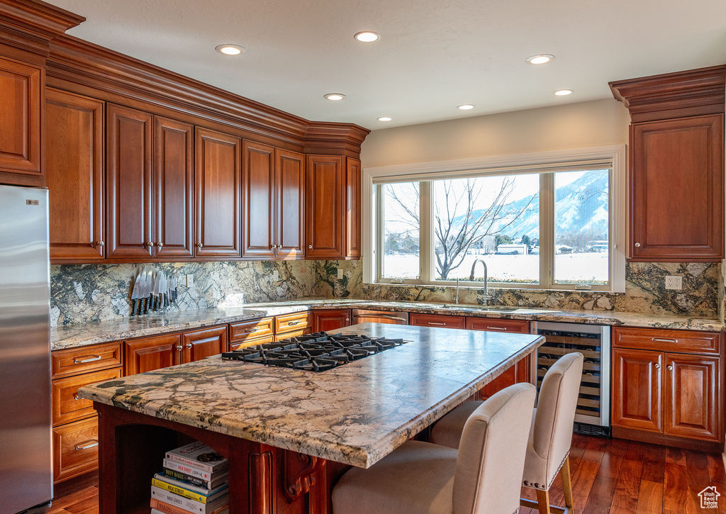 Kitchen featuring appliances with stainless steel finishes, a kitchen bar, a center island, dark hardwood / wood-style floors, and wine cooler