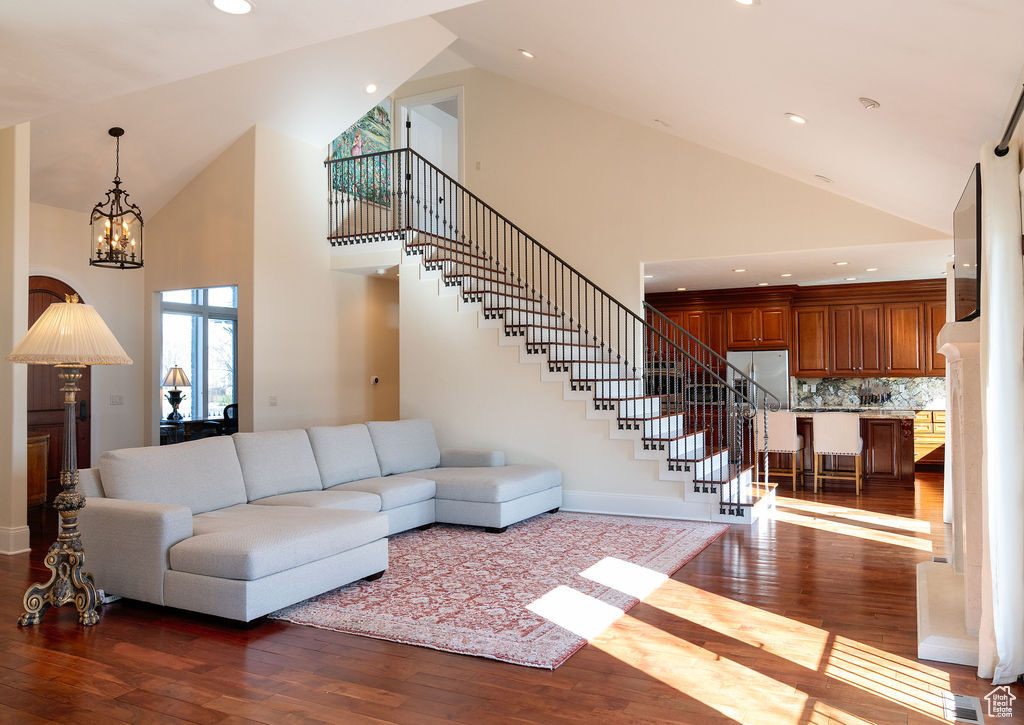 Living room featuring dark hardwood / wood-style flooring, high vaulted ceiling, and an inviting chandelier