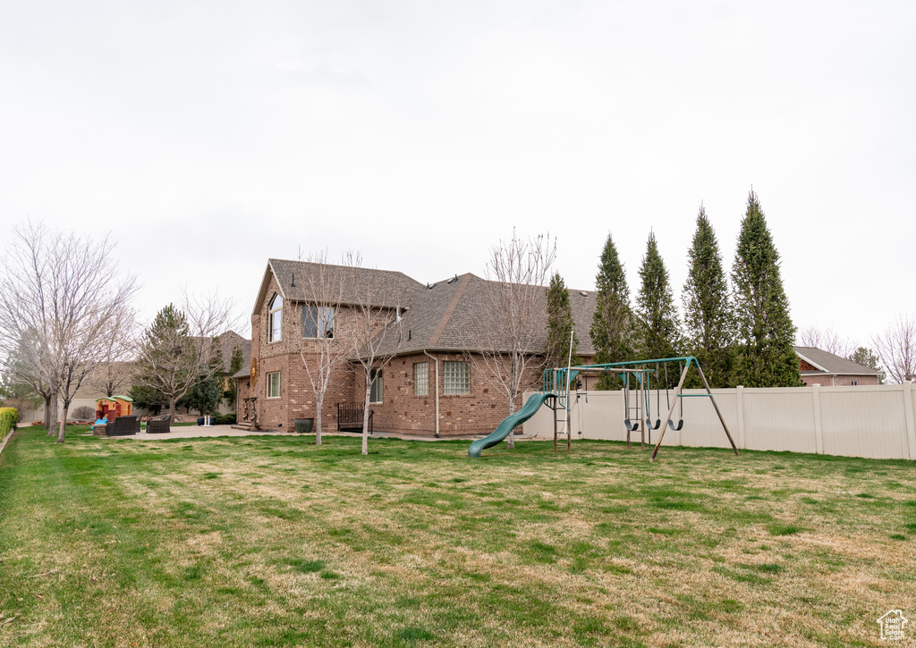 View of yard with a playground, fence, and a patio area