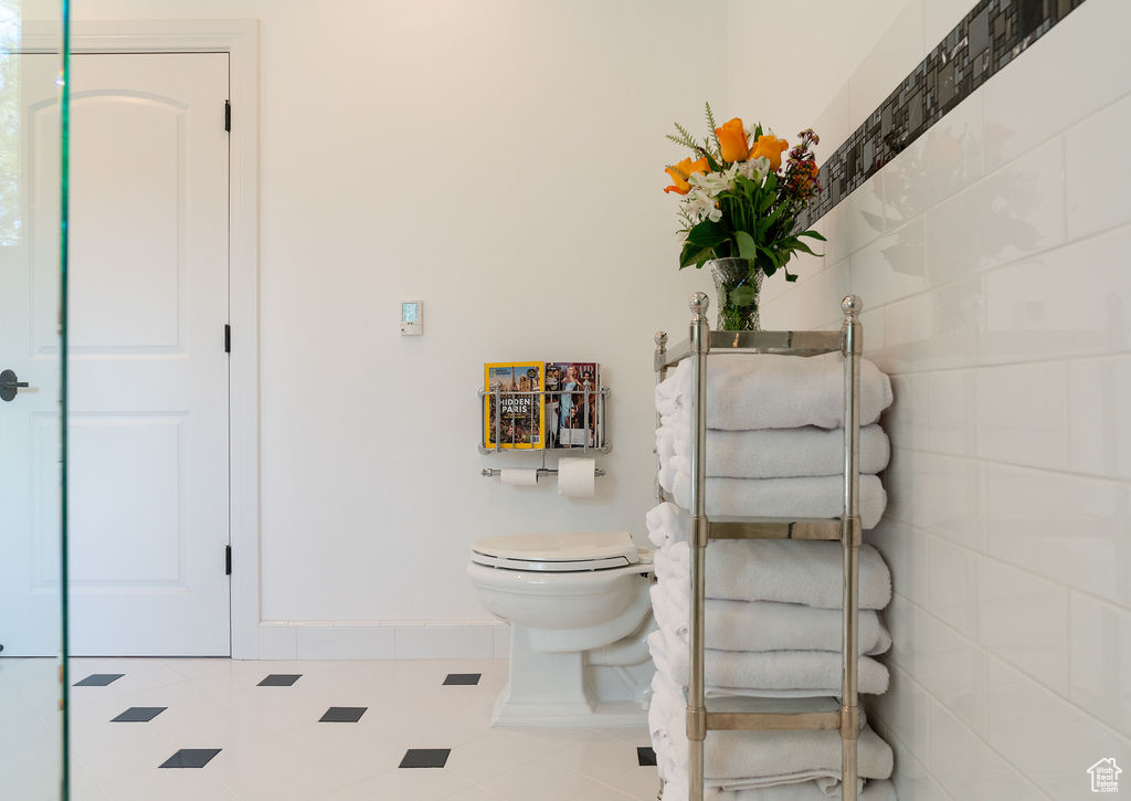 Bathroom with tile patterned floors, toilet, and tile walls