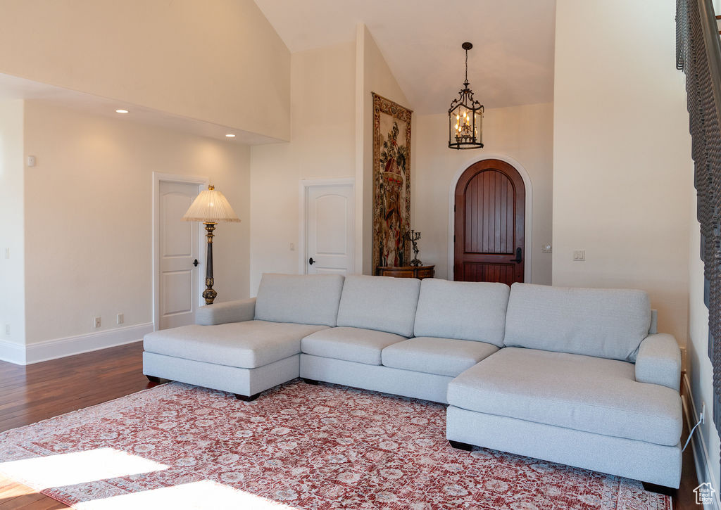 Living room featuring an inviting chandelier, high vaulted ceiling, and wood-type flooring