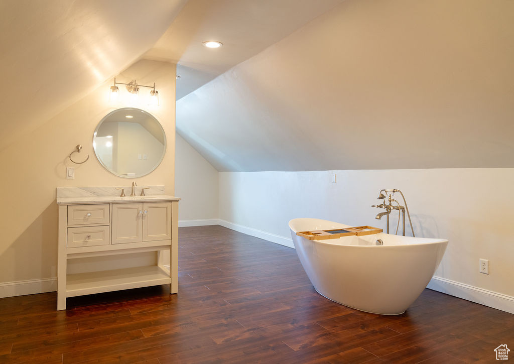 Bathroom with lofted ceiling, wood-type flooring, a bathtub, and vanity