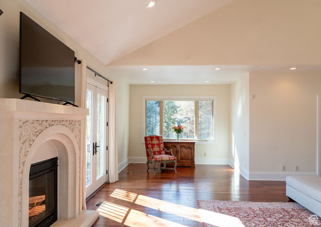 Living area featuring a fireplace, high vaulted ceiling, and hardwood / wood-style floors