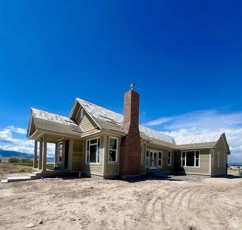 Rear view of house featuring covered porch and a chimney