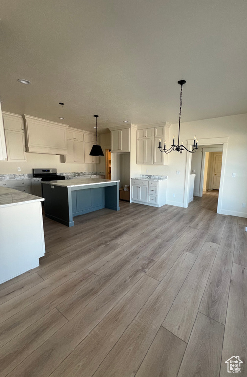 Kitchen featuring a chandelier, light wood-style floors, white cabinetry, light countertops, and open floor plan